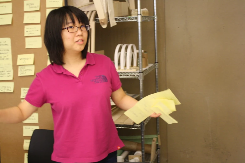 a woman in a pink shirt is holding papers