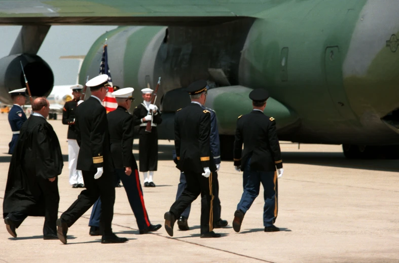 men are dressed in uniform walking to an airplane