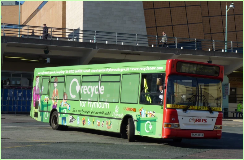 a green, red and white bus parked at a bus stop