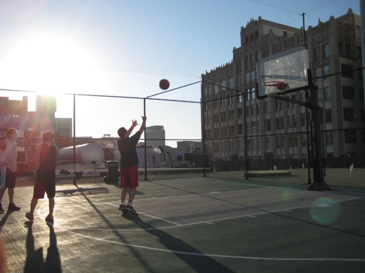 two men play basketball on a court in a large city