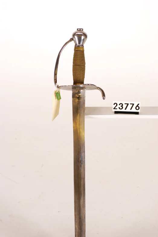 a metal sword with a yellow handle and a black top with a cord and a metal rod on it