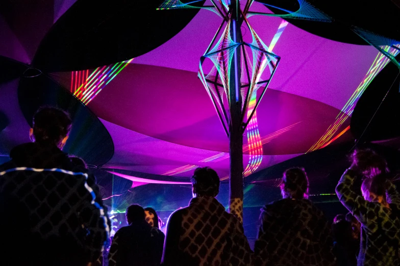 group of people standing under an umbrella covered by colored lights