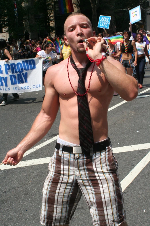 a shirtless man with tie, standing in a street