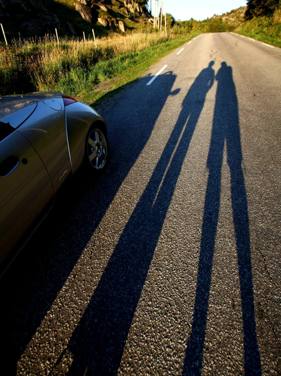 the shadows of two people standing on top of a car