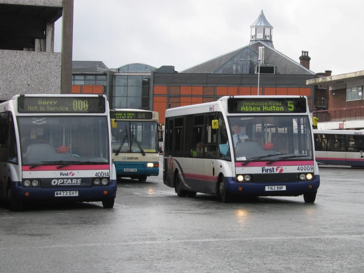 two passenger buses on a wet city street