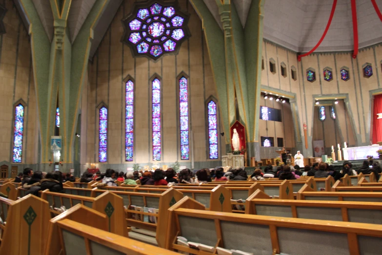 people sitting in pews with stained glass windows