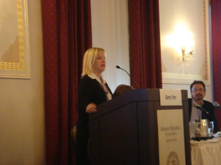 the man is talking at the podium while the woman is standing up