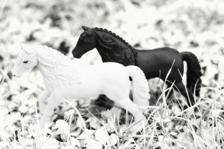 a couple of toy horses in a field of flowers