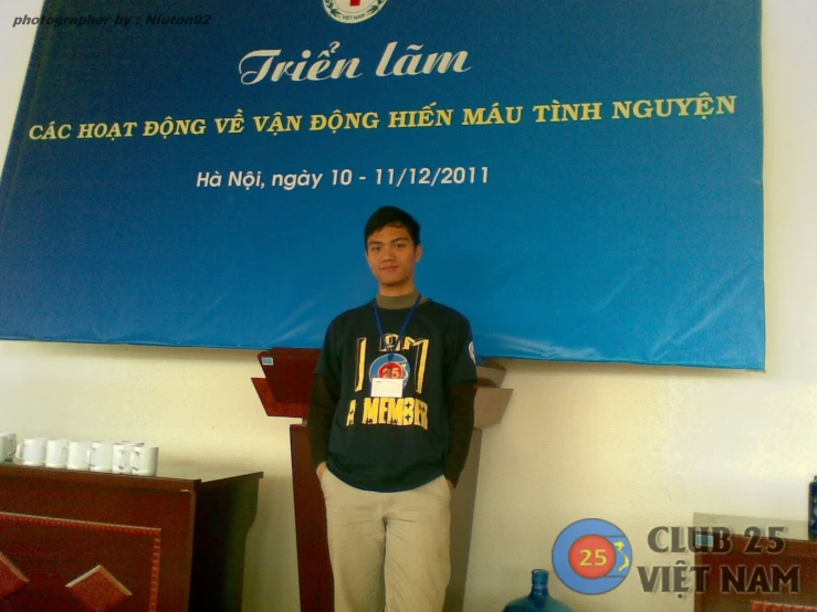 a young man standing in front of a large blue poster