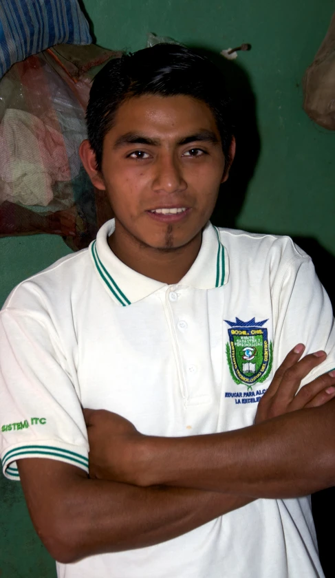 a man with his arms crossed, in front of green wall