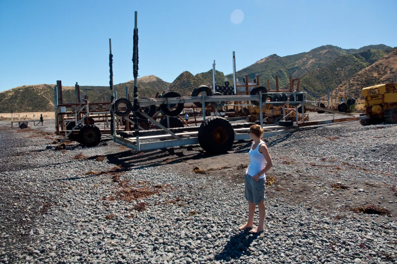 a woman in a white top stands by some old machinery