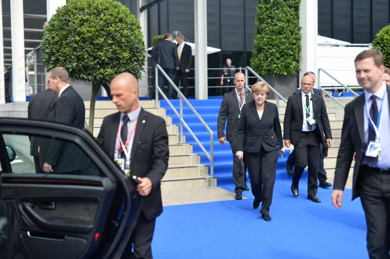 many business people wearing suits and ties are going down the blue carpet