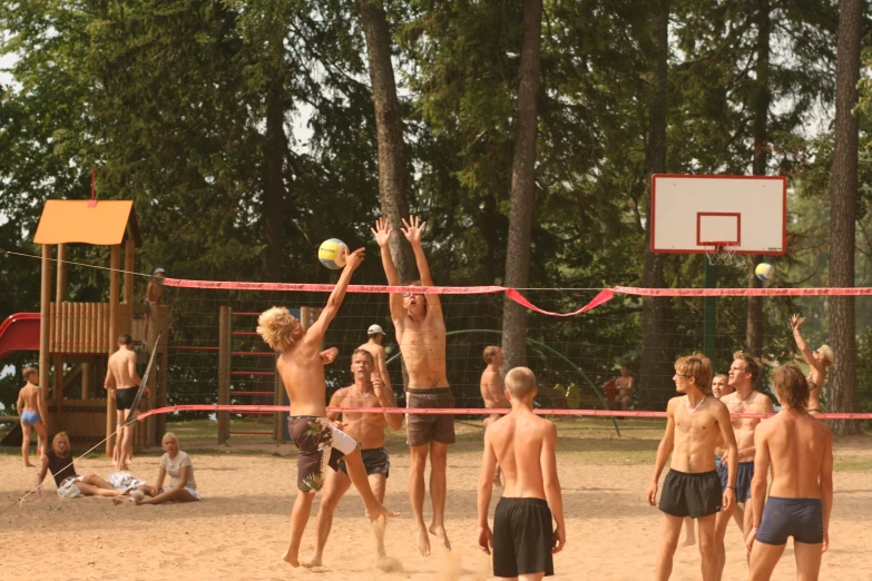 several boys on a beach playing a game with volley ball