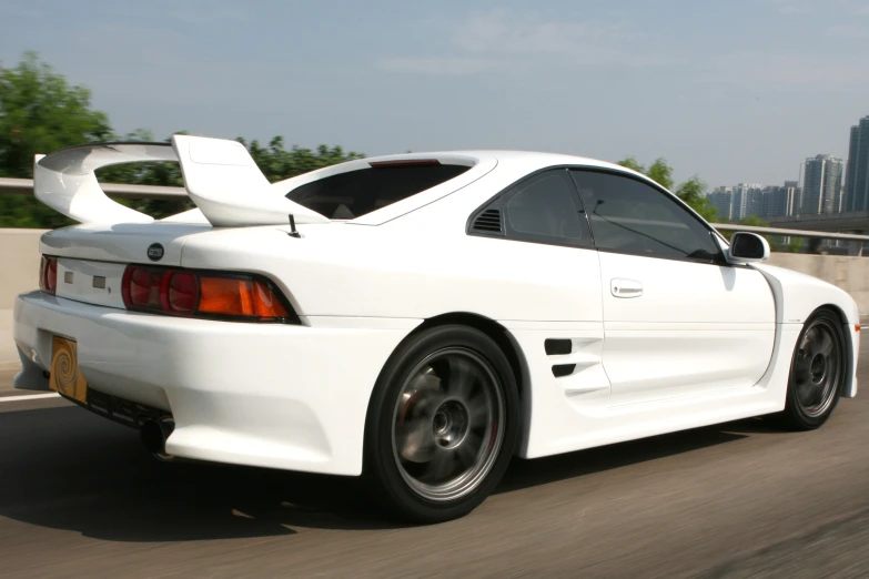 a white sports car on a street with city buildings in background