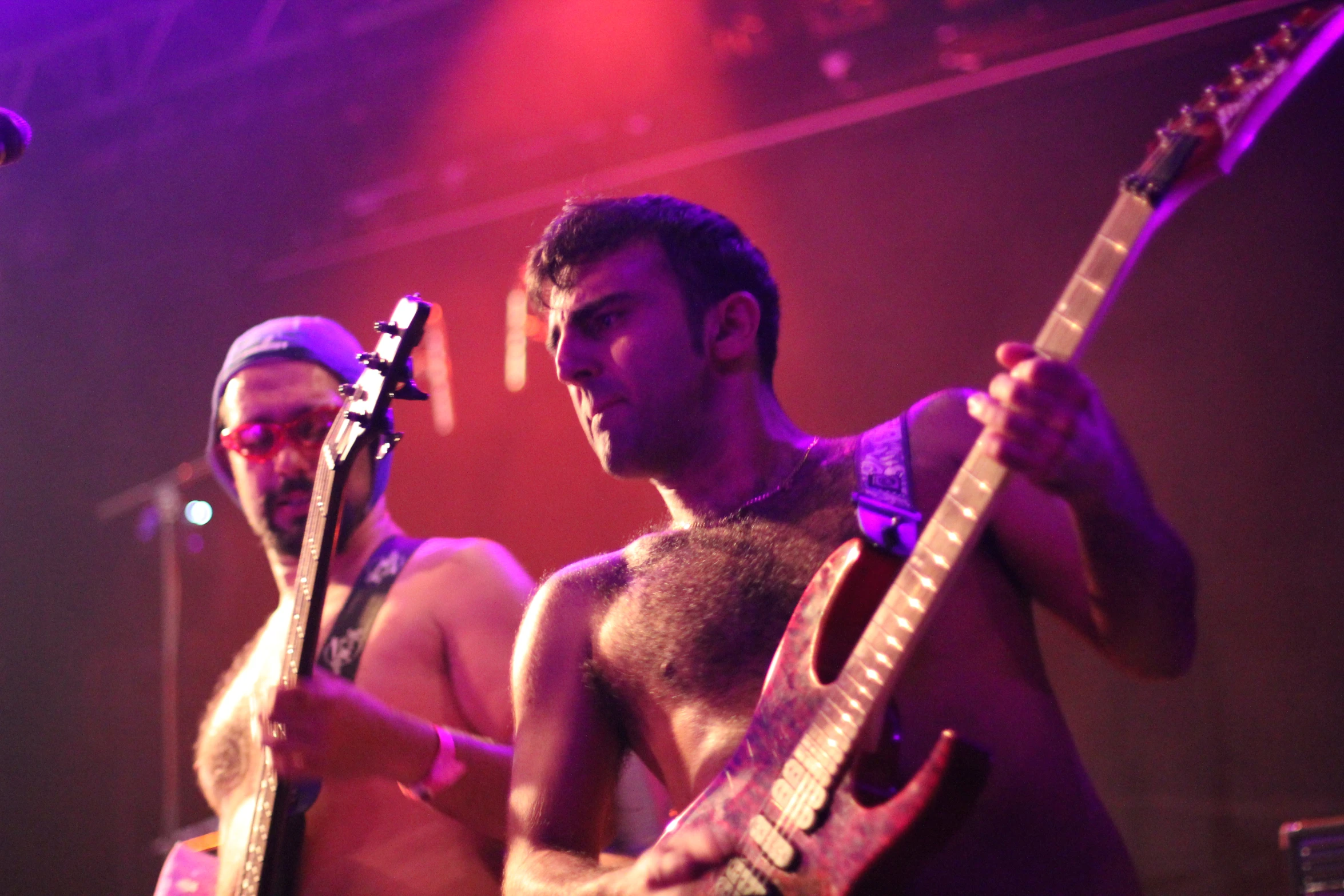 two men are playing guitar while standing on stage