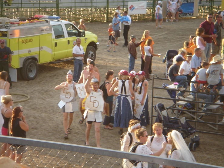 a crowd of people walking across a dirt field