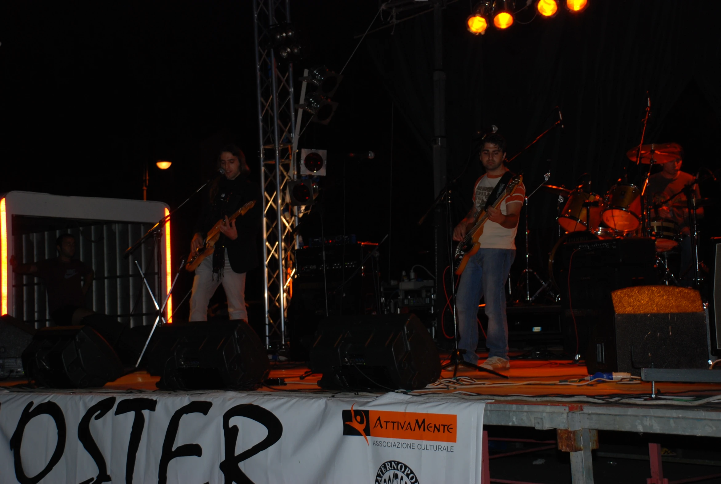 three men playing guitars on stage at night