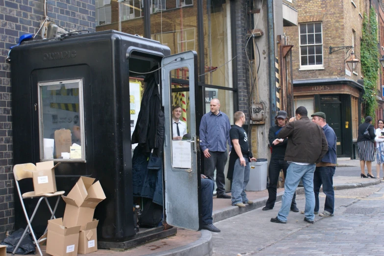 a man is standing outside in front of a broken cell phone booth