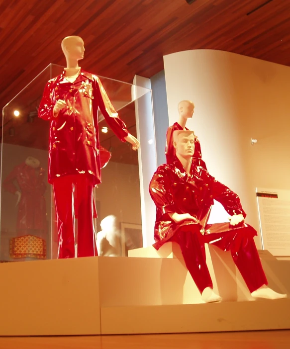 three mannequins sitting in front of a large window