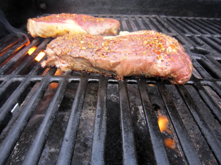 steaks and meat sitting on the grill ready to go in the oven