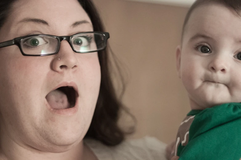 a lady holds up a baby with her mouth open