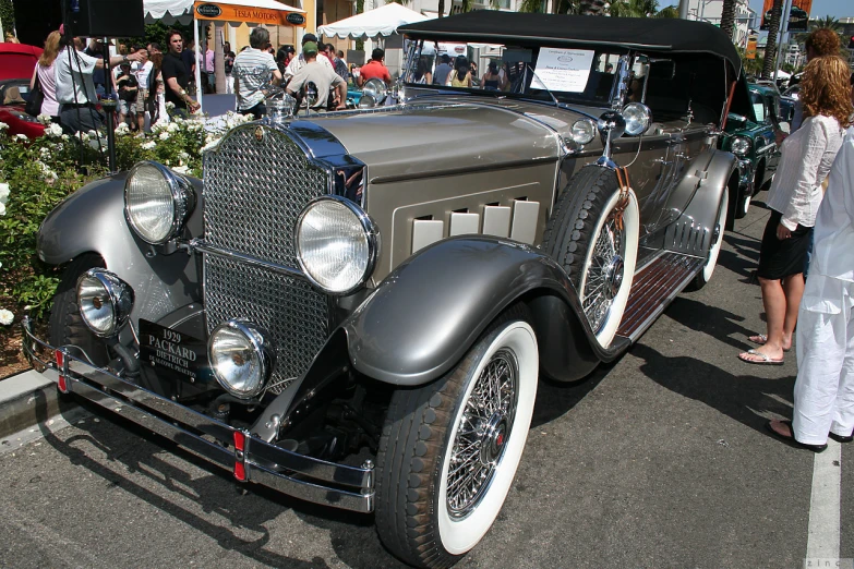 an antique silver car parked on the side of a road