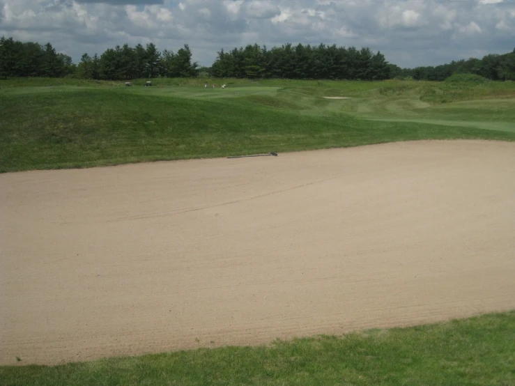 a sand pit surrounded by green and cloudy skies