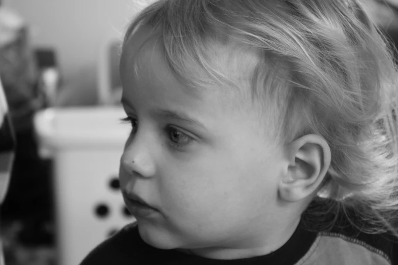 a baby girl looks down while she's holding onto a hairdryer