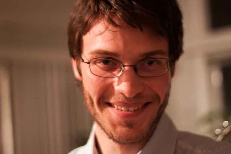 a man wearing glasses smiles at the camera