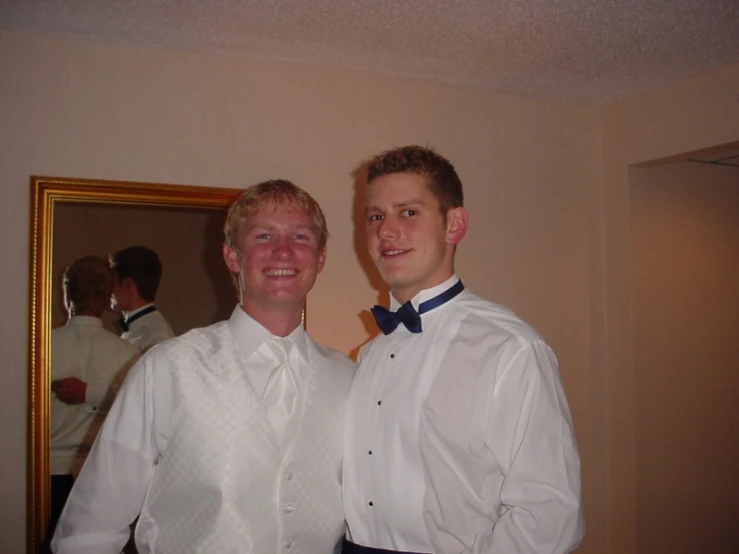 two young men wearing formal clothes in front of a mirror