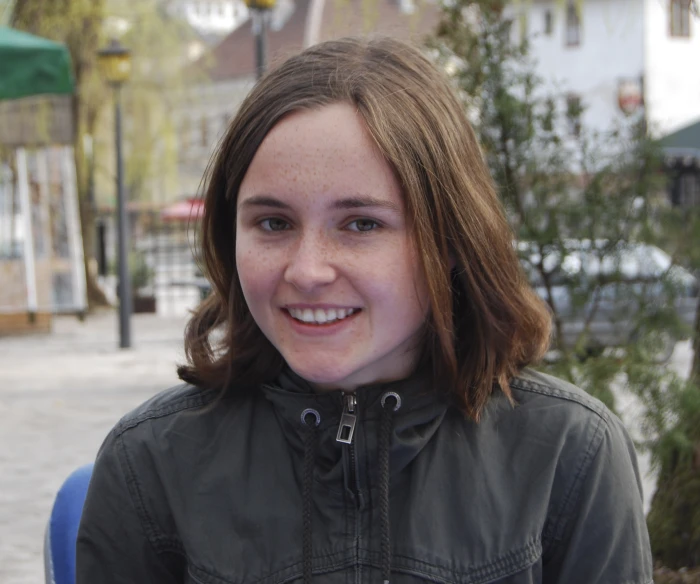 a girl with an apple slice in her hand smiling