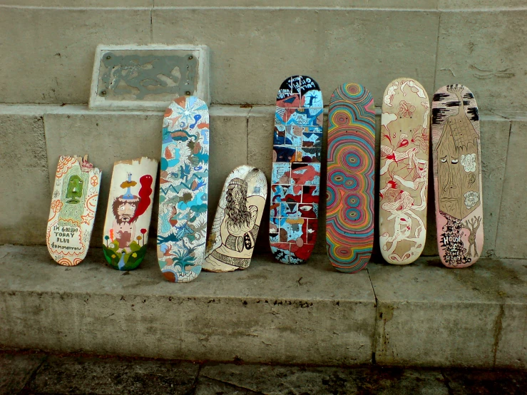 seven skateboards laid out on a stone ledge