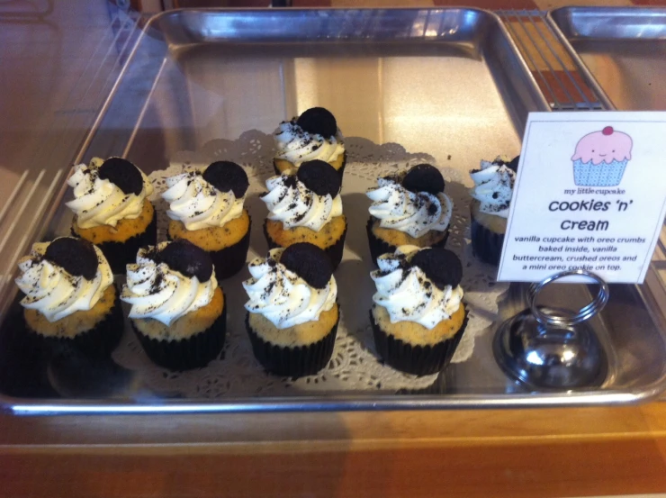 a tray with many decorated cupcakes for sale