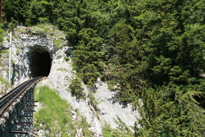 an old train travels down some tracks through a wooded area