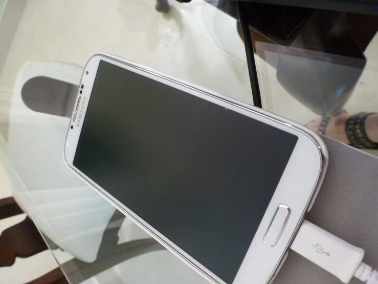 a white samsung cell phone charging in an exhibit