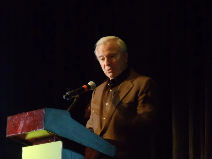 man standing at a podium speaking into microphone