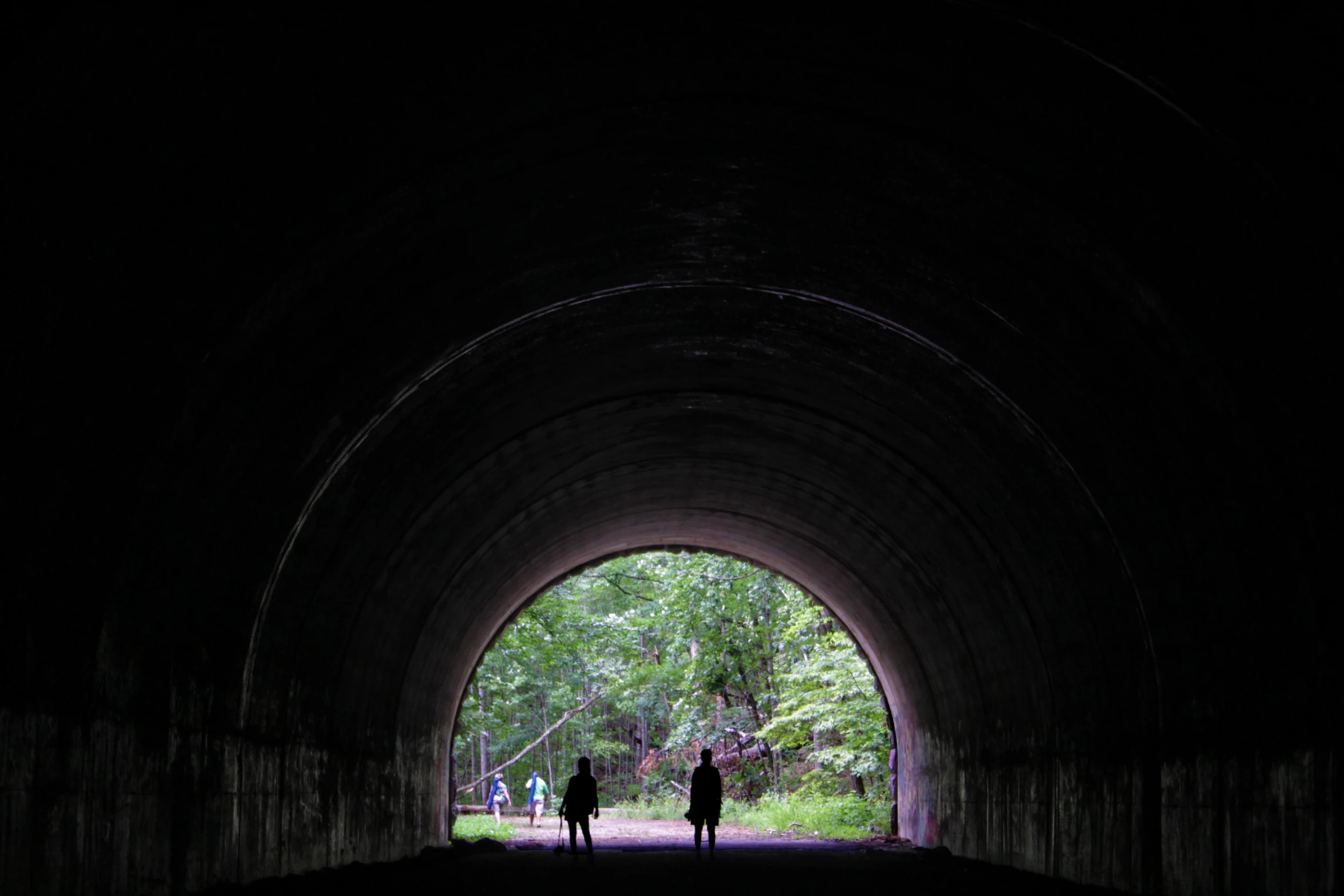 two people walking in the middle of a tunnel