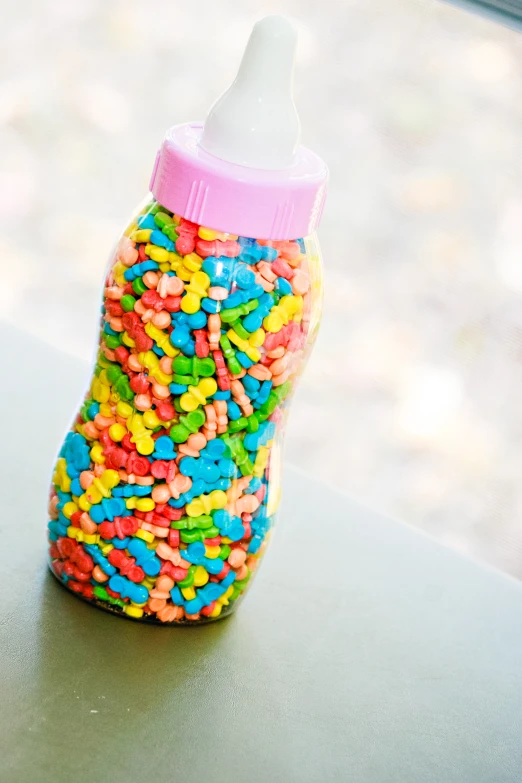 a bottle full of colorful sprinkles sitting on top of a counter