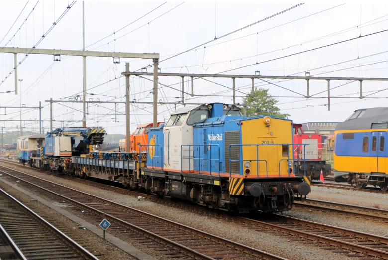 two trains are parked on tracks with power lines above them