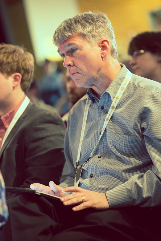 two men sitting and one is holding his tablet