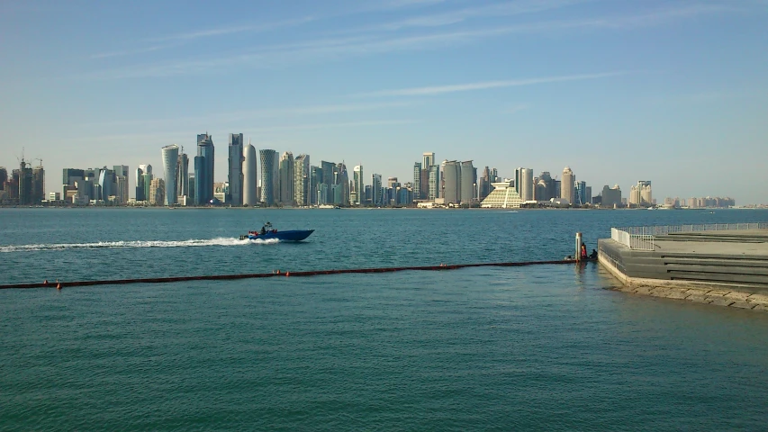 the small motor boat is headed to shore with city in background