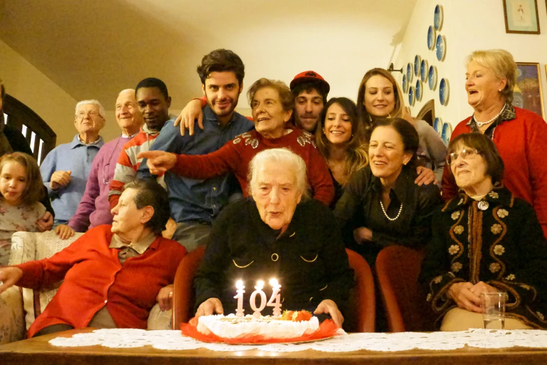 group of people posing around a happy birthday cake