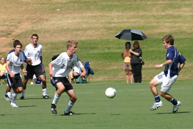 several men playing soccer on a field under an umbrella