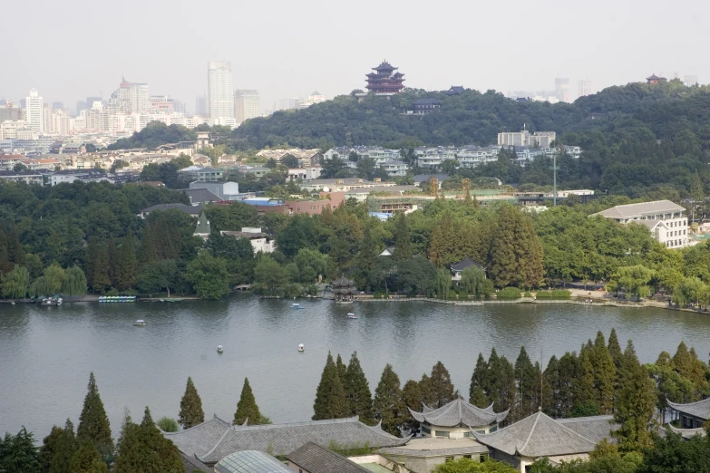 a city area with trees in the foreground, and a lake, with mountains in the background