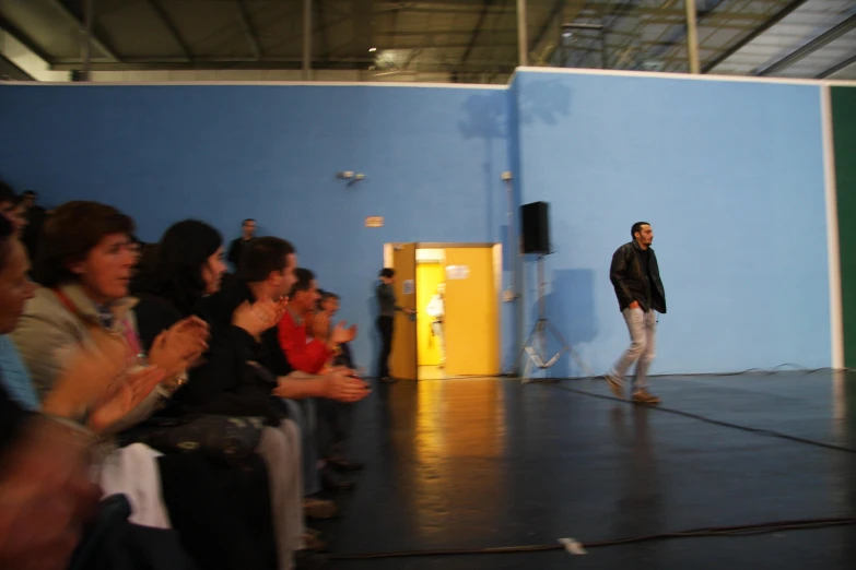 a man in a black jacket walking on a runway