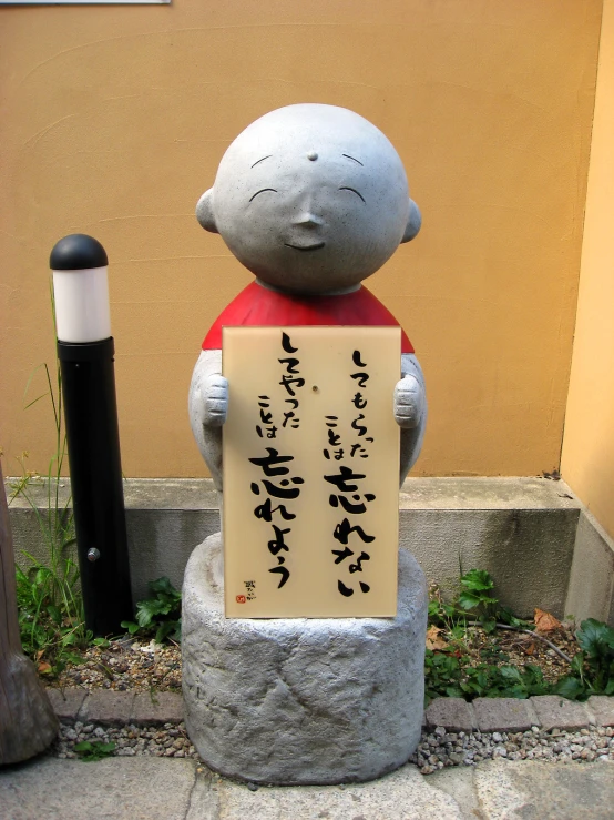 a statue of a boy holding a sign