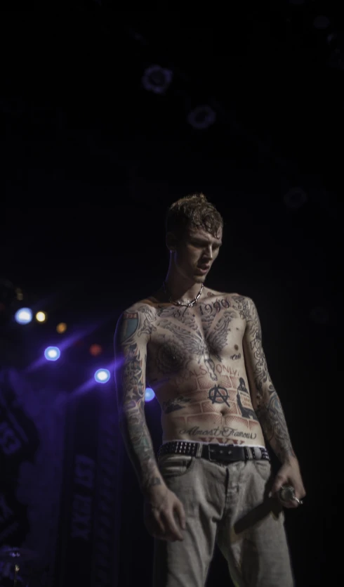 a tattooed man standing in the dark