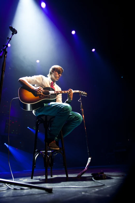 a man with a guitar sitting in a chair