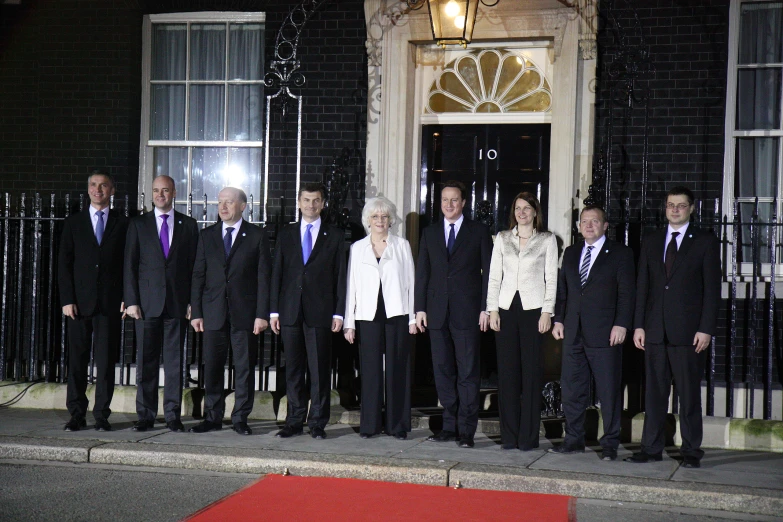 a group of people posing for a pograph in front of a black building