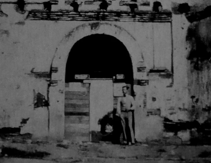 an old po shows a man and dog on the door way